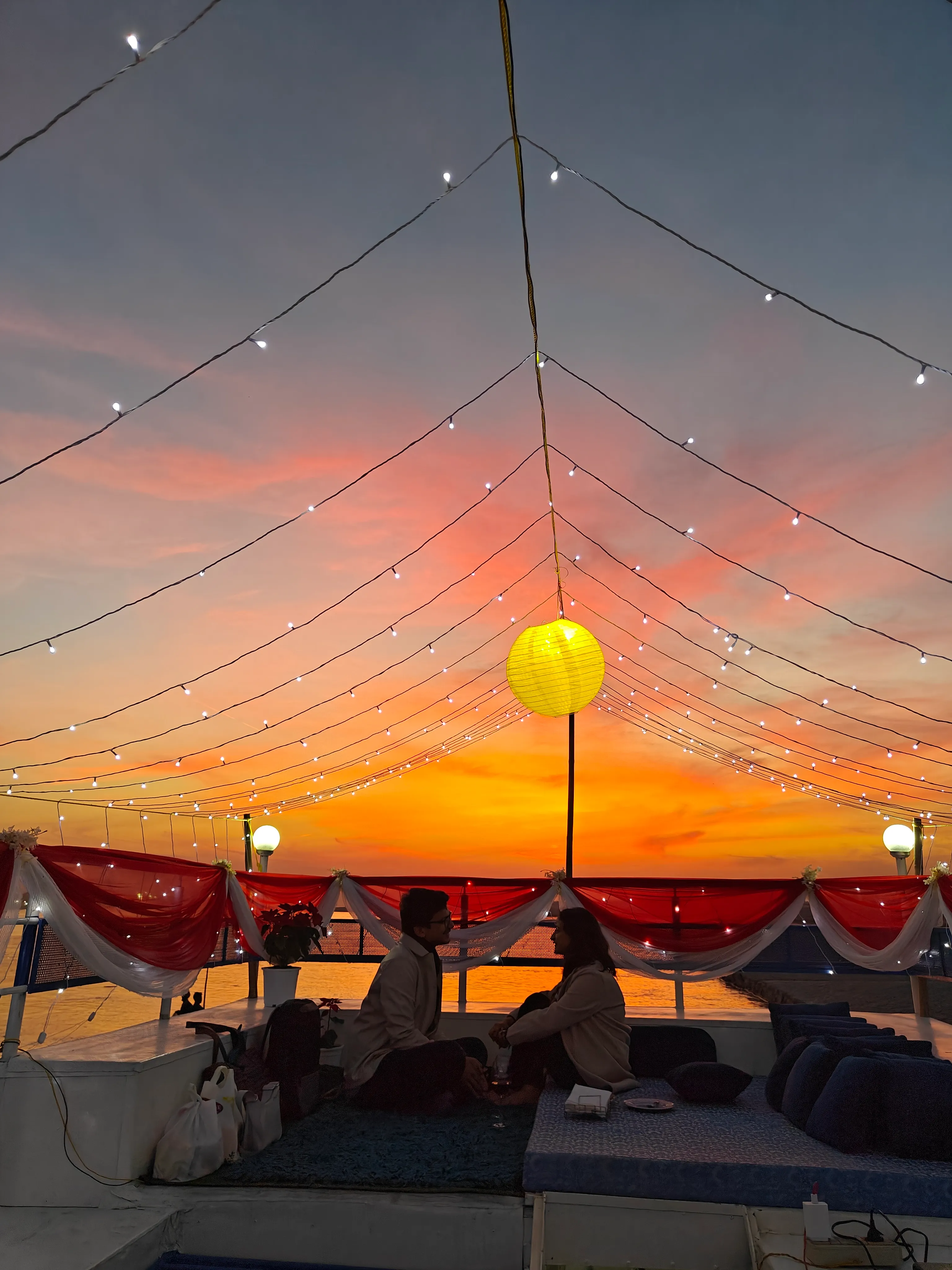 Couple at a candlelit table under a lit canopy on a private cruise