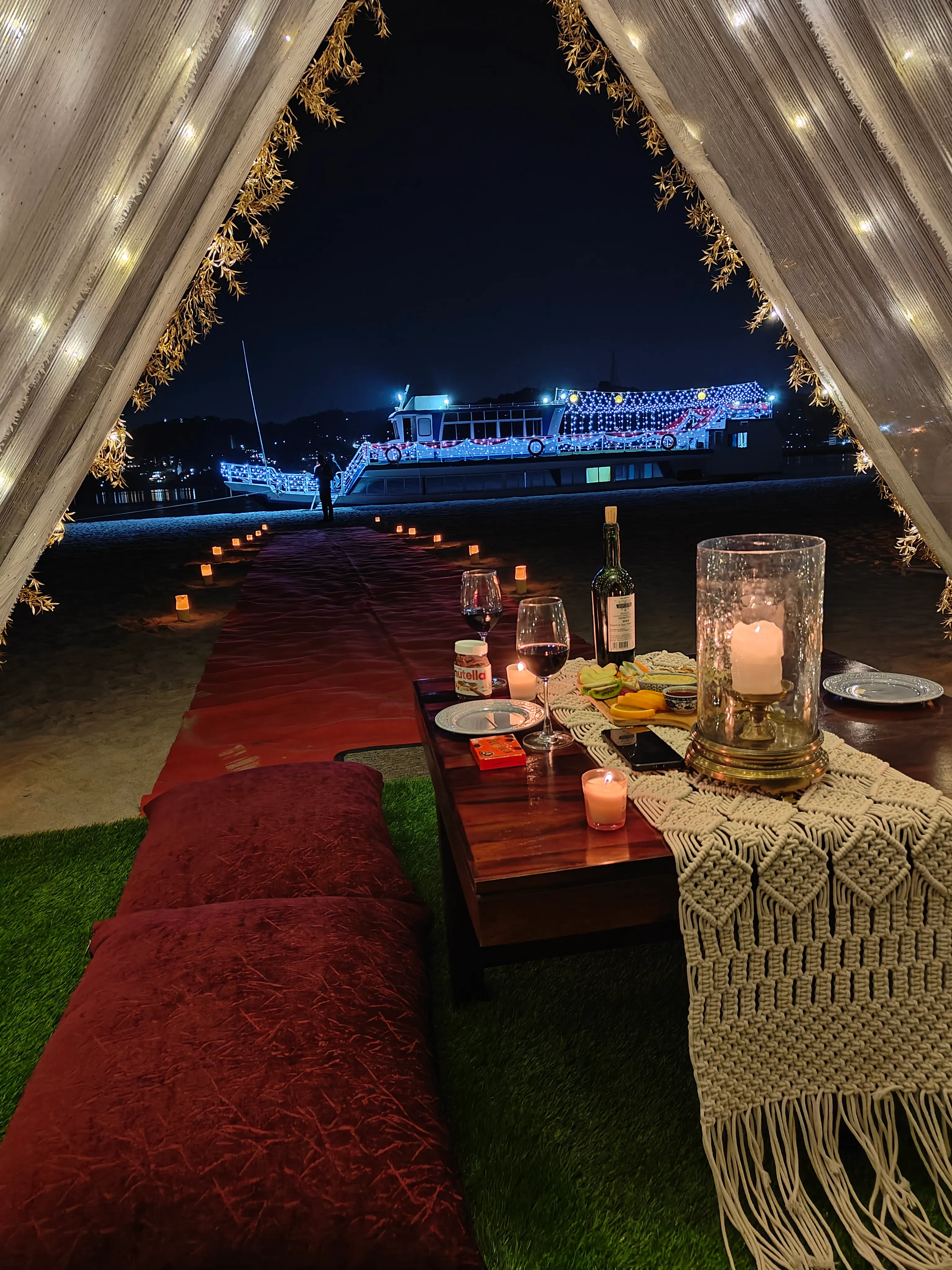 View from the island dinner tent toward the lit vessel across the sand