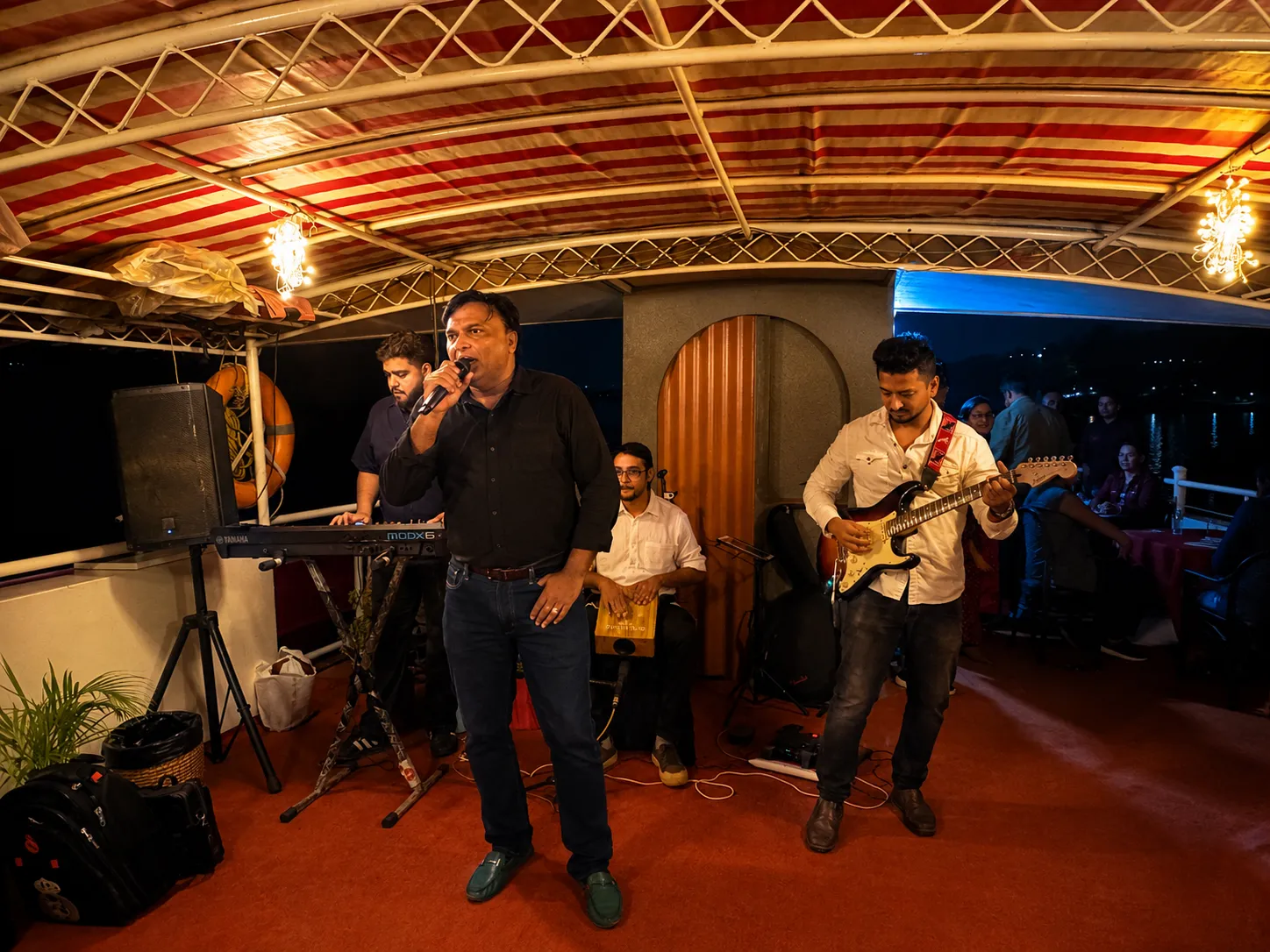 Live band with singer and guitarist playing under the canopy of S B Serene at night