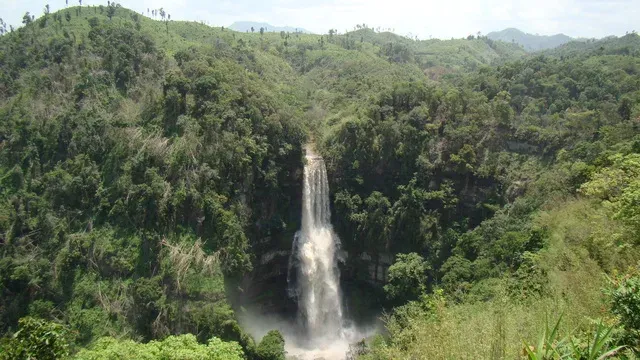 Vantawng Falls plunging in a long white column down a forested cliff face, dense green jungle closing around the gorge on every side
