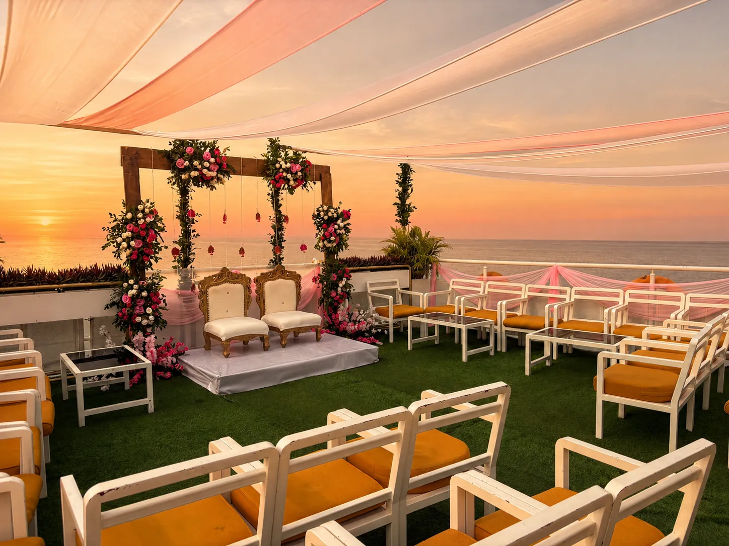Floral wedding stage with drapes and couple seats set on the upper deck at sunset
